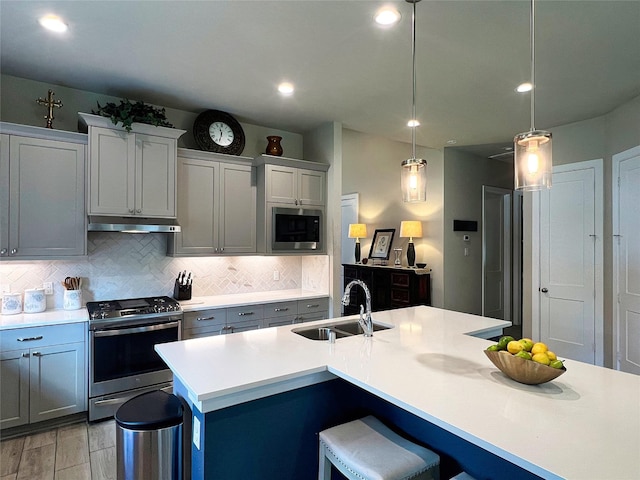 2 Ruchill Cir, Conroe, TX 77304 - kitchen featuring appliances with stainless steel finishes, under cabinet range hood, tasteful backsplash, light countertops, and a kitchen breakfast bar