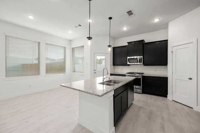 7810 Starfish Arbor Dr, Cypress, TX 77433 - kitchen featuring appliances with stainless steel finishes, dark cabinetry, light wood-style floors, decorative backsplash, and recessed lighting