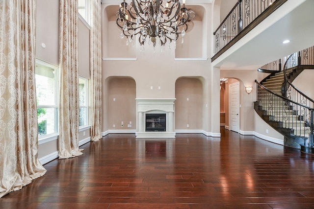 25518 Millbrook Bend Ln, Katy, TX 77494 - unfurnished living room featuring a chandelier, a towering ceiling, wood-type flooring, arched walkways, and stairs