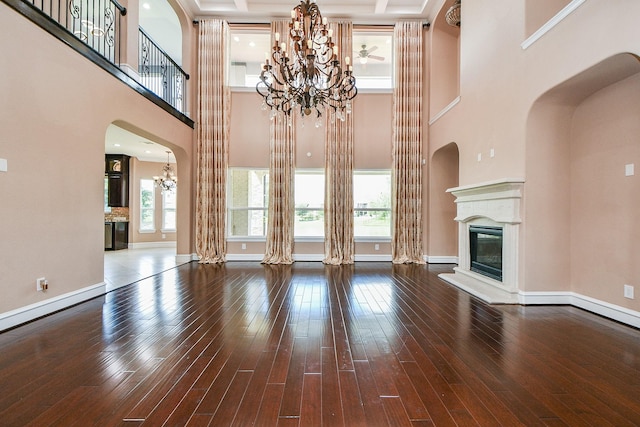 25518 Millbrook Bend Ln, Katy, TX 77494 - unfurnished living room with a chandelier, a fireplace, hardwood / wood-style floors, a high ceiling, and arched walkways