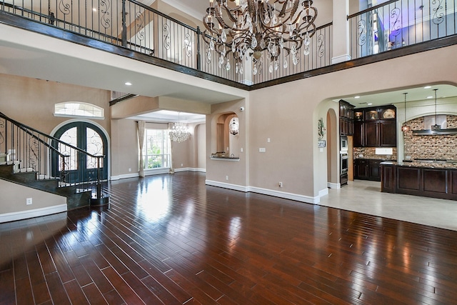 25518 Millbrook Bend Ln, Katy, TX 77494 - unfurnished living room with a chandelier, arched walkways, a high ceiling, stairs, and wood finished floors