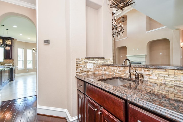 25518 Millbrook Bend Ln, Katy, TX 77494 - kitchen with arched walkways, crown molding, stone countertops, tasteful backsplash, and dark brown cabinets