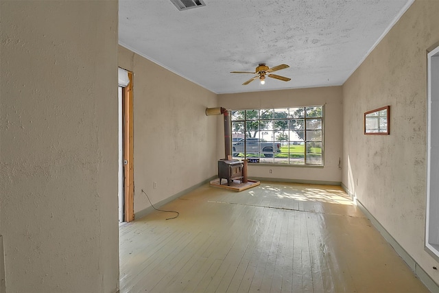 531 Circle Dr, La Porte, TX 77571 - unfurnished room featuring a wood stove, hardwood / wood-style floors, a ceiling fan, a textured wall, and a textured ceiling