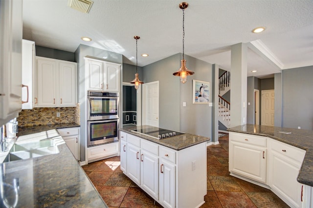 11715 Orchard Mountain Dr, Pasadena, TX 77059 - kitchen with double oven, black electric cooktop, tasteful backsplash, a kitchen island, and hanging light fixtures