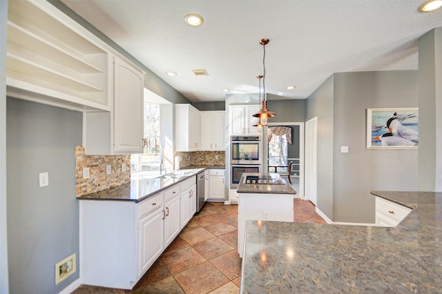 11715 Orchard Mountain Dr, Pasadena, TX 77059 - kitchen featuring appliances with stainless steel finishes, tasteful backsplash, a kitchen island, white cabinets, and hanging light fixtures