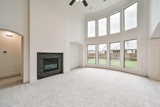 17794 Misty Brook Ln, Conroe, TX 77302 - unfurnished living room with a towering ceiling, carpet, ceiling fan, a glass covered fireplace, and arched walkways