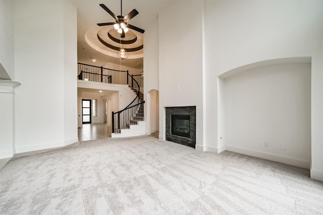 17794 Misty Brook Ln, Conroe, TX 77302 - unfurnished living room featuring a towering ceiling, stairs, ceiling fan, carpet flooring, and a premium fireplace
