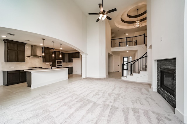 17794 Misty Brook Ln, Conroe, TX 77302 - unfurnished living room featuring a high ceiling, ceiling fan, arched walkways, a glass covered fireplace, and stairs
