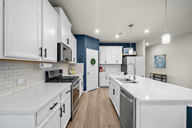 2218 Royal Ann Way, Tomball, TX 77375 - kitchen featuring appliances with stainless steel finishes, light countertops, tasteful backsplash, light wood-style flooring, and white cabinetry