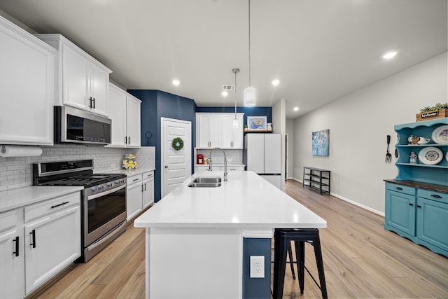 2218 Royal Ann Way, Tomball, TX 77375 - kitchen featuring stainless steel appliances, backsplash, light wood-type flooring, a kitchen bar, and white cabinets