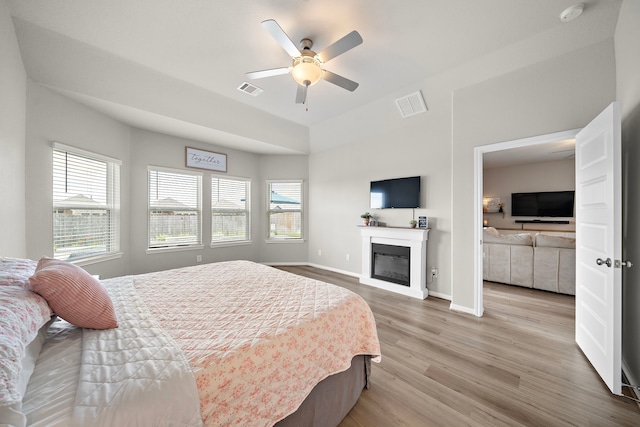 2218 Royal Ann Way, Tomball, TX 77375 - bedroom with light wood-type flooring, a glass covered fireplace, and a ceiling fan