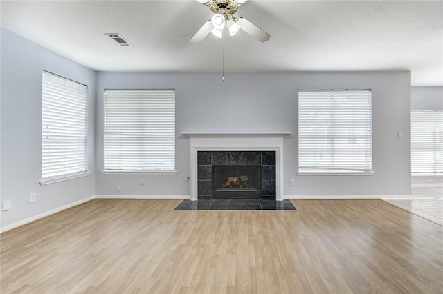 16023 Cutten Rd, Houston, TX 77070 - unfurnished living room with wood finished floors, a ceiling fan, a tiled fireplace, and healthy amount of natural light
