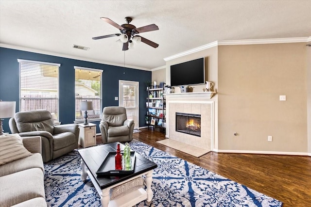 4472 Gerona St, League City, TX 77573 - living room featuring ceiling fan, wood finished floors, crown molding, a tiled fireplace, and a textured ceiling