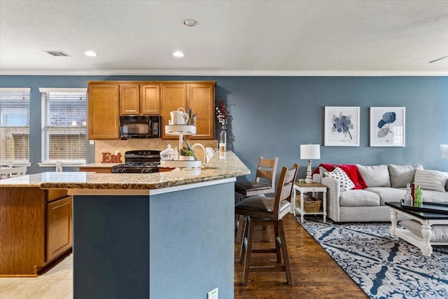4472 Gerona St, League City, TX 77573 - kitchen with black appliances, ornamental molding, backsplash, light stone countertops, and a kitchen breakfast bar