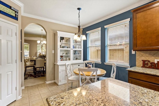 4472 Gerona St, League City, TX 77573 - dining space featuring a chandelier, arched walkways, light tile patterned floors, and crown molding