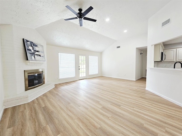 14519 Cypress Valley Dr, Cypress, TX 77429 - unfurnished living room featuring vaulted ceiling, a textured ceiling, a brick fireplace, light wood-style flooring, and ceiling fan
