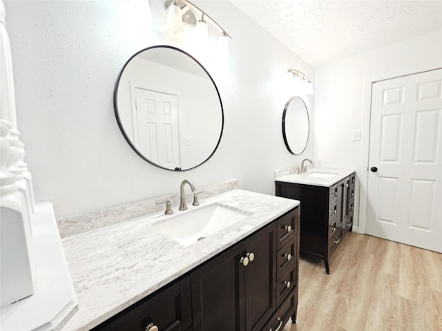 14519 Cypress Valley Dr, Cypress, TX 77429 - bathroom featuring two vanities, wood finished floors, and a textured ceiling