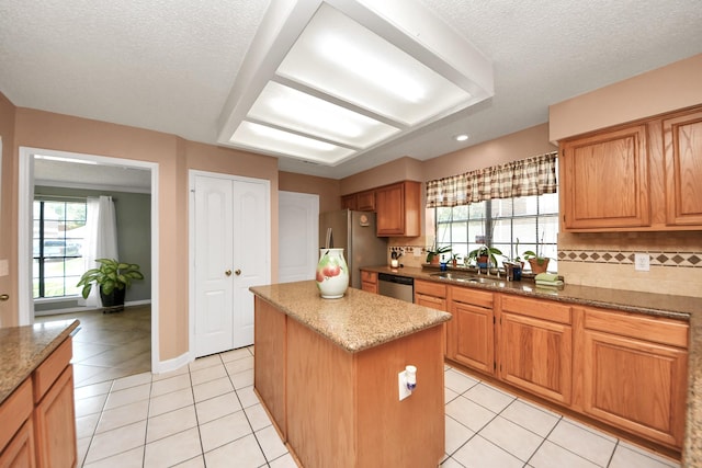 3107 Dulaney Rd, Houston, TX 77084 - kitchen featuring appliances with stainless steel finishes, a kitchen island, backsplash, light tile patterned flooring, and a textured ceiling