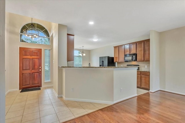 4473 Gran Canary Dr, League City, TX 77573 - kitchen with black appliances, stone countertops, brown cabinets, hanging light fixtures, and recessed lighting