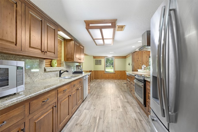 14590 N Tram Rd, Splendora, TX 77372 - kitchen with stainless steel appliances, ventilation hood, brown cabinets, light wood finished floors, and wood walls