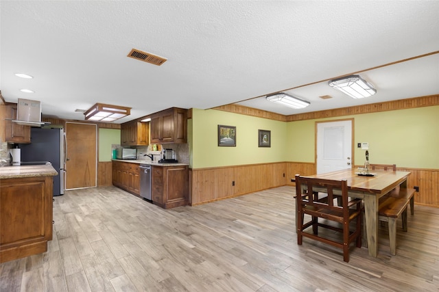 14590 N Tram Rd, Splendora, TX 77372 - dining area featuring a wainscoted wall, light wood-style floors, wooden walls, and a textured ceiling