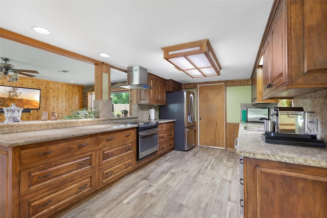 14590 N Tram Rd, Splendora, TX 77372 - kitchen with appliances with stainless steel finishes, island range hood, light wood-style floors, and brown cabinets