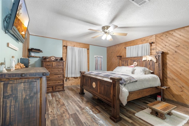 14590 N Tram Rd, Splendora, TX 77372 - bedroom with wood walls, wood finished floors, a textured ceiling, and a ceiling fan