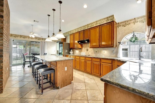 14523 Hillside Hickory Ct, Houston, TX 77062 - kitchen with under cabinet range hood, a ceiling fan, a center island, brown cabinetry, and recessed lighting