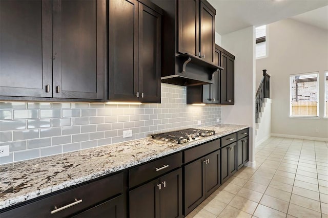 24239 Oakland Mist Ln, Katy, TX 77494 - kitchen featuring stainless steel gas stovetop, decorative backsplash, light tile patterned floors, and light stone countertops
