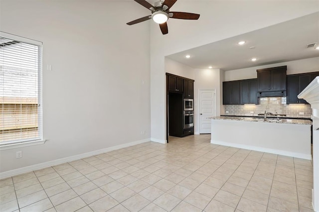 24239 Oakland Mist Ln, Katy, TX 77494 - kitchen featuring appliances with stainless steel finishes, under cabinet range hood, a ceiling fan, tasteful backsplash, and a towering ceiling