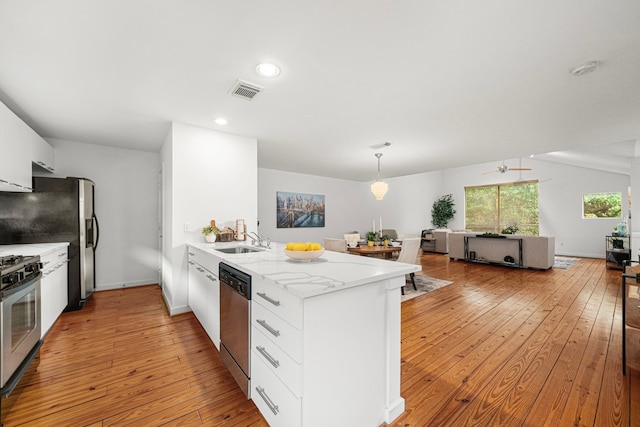 2712 La Branch St, Houston, TX 77004 - kitchen with stainless steel appliances, a peninsula, white cabinets, light wood finished floors, and recessed lighting