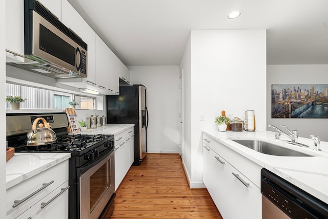 2712 La Branch St, Houston, TX 77004 - kitchen with stainless steel appliances, light wood-type flooring, recessed lighting, white cabinetry, and light stone countertops