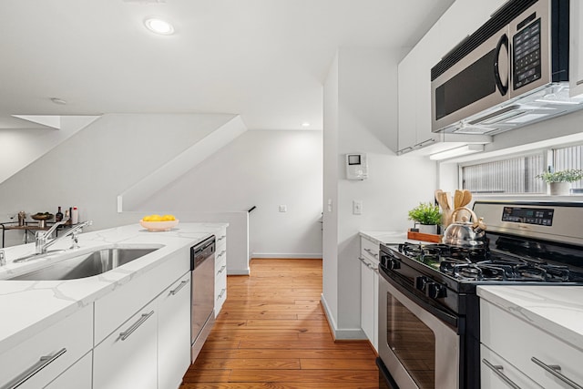 2712 La Branch St, Houston, TX 77004 - kitchen with stainless steel appliances, light wood-style floors, recessed lighting, white cabinetry, and light stone countertops