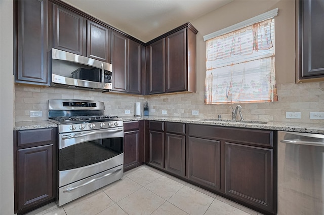 19547 Stetson Heights Ln, Richmond, TX 77407 - kitchen featuring stainless steel appliances, light tile patterned flooring, dark brown cabinets, light stone counters, and backsplash
