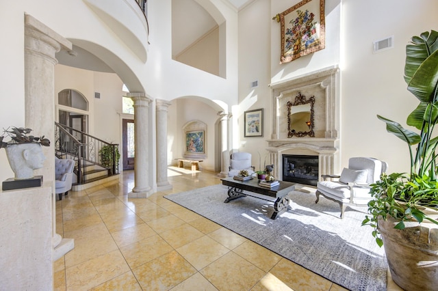 7615 San Clemente Point Ct, Katy, TX 77494 - tiled living area featuring ornate columns, arched walkways, a towering ceiling, a glass covered fireplace, and stairs