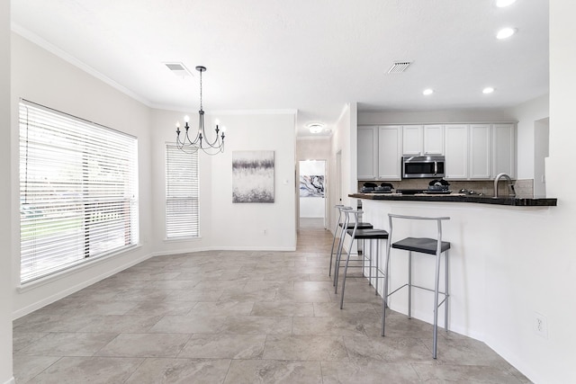 23010 Adwick Ct, Katy, TX 77450 - kitchen featuring stainless steel microwave, a chandelier, a kitchen bar, dark countertops, and backsplash