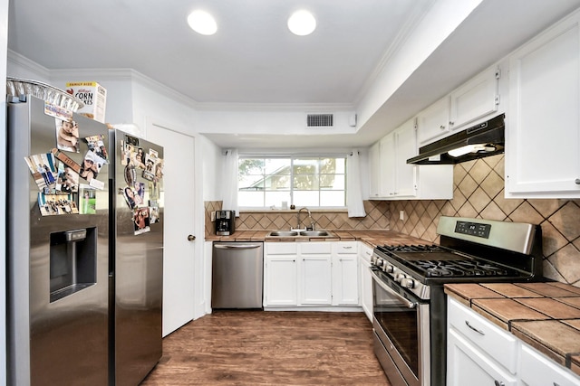 7726 Sorbete Dr, Houston, TX 77083 - kitchen featuring stainless steel appliances, under cabinet range hood, tile counters, crown molding, and white cabinets