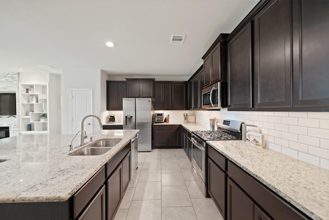 1205 Citruswood Trail Ln, Rosenberg, TX 77471 - kitchen featuring stainless steel appliances, backsplash, light stone countertops, light tile patterned floors, and a kitchen island with sink