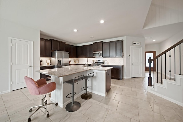 1205 Citruswood Trail Ln, Rosenberg, TX 77471 - kitchen with stainless steel appliances, tasteful backsplash, a kitchen island with sink, light stone countertops, and a breakfast bar