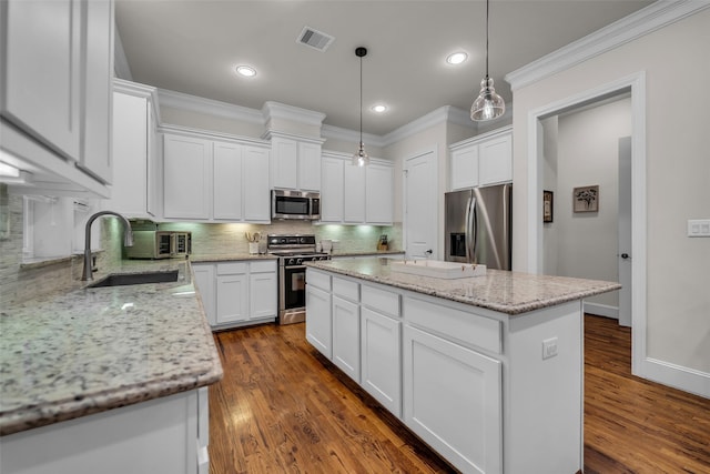 8720 Kempwood Dr, Houston, TX 77080 - kitchen with appliances with stainless steel finishes, a kitchen island, ornamental molding, white cabinetry, and decorative backsplash