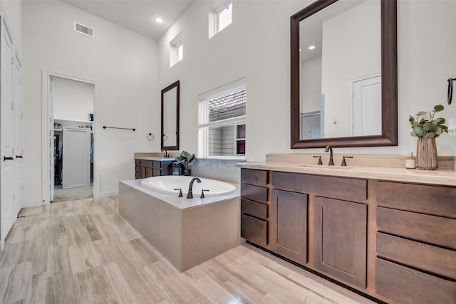 8720 Kempwood Dr, Houston, TX 77080 - bathroom featuring a bath, vanity, a high ceiling, wood finished floors, and recessed lighting