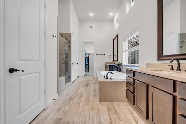 8720 Kempwood Dr, Houston, TX 77080 - full bath featuring a stall shower, a garden tub, two vanities, wood finished floors, and recessed lighting