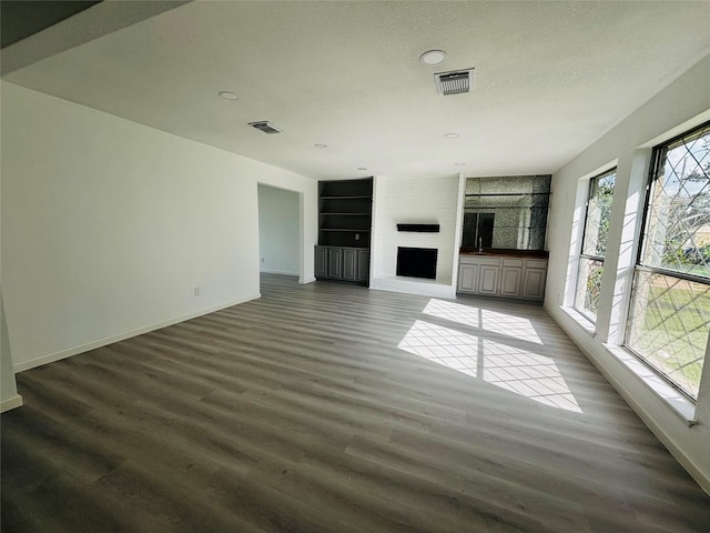 16246 Los Altos Dr, Houston, TX 77083 - unfurnished living room with wood finished floors, a fireplace, built in shelves, recessed lighting, and a textured ceiling