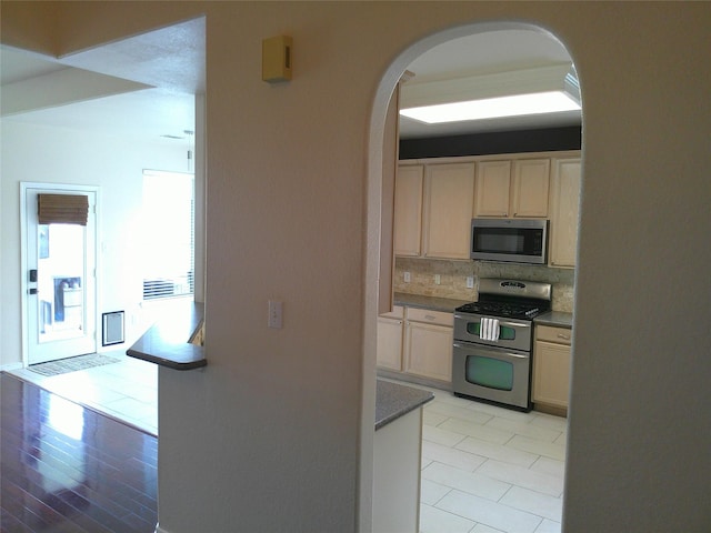 3307 Norma Ln, Pearland, TX 77584 - kitchen featuring appliances with stainless steel finishes, arched walkways, backsplash, and light wood finished floors
