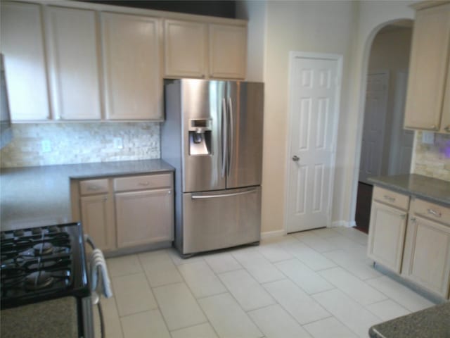 3307 Norma Ln, Pearland, TX 77584 - kitchen with stainless steel fridge with ice dispenser, black gas range, arched walkways, tasteful backsplash, and dark countertops