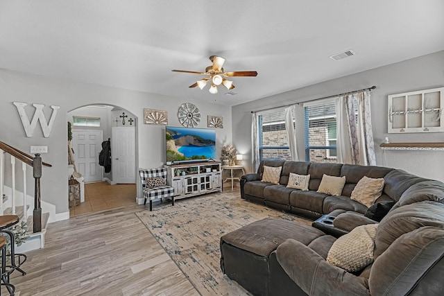 8315 Egret Bay Cir, Baytown, TX 77523 - living room featuring arched walkways, a ceiling fan, stairway, and light wood-type flooring