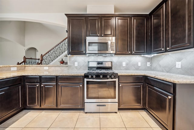 1306 S Maple Dr, Katy, TX 77493 - kitchen with appliances with stainless steel finishes, arched walkways, light stone countertops, and light tile patterned floors