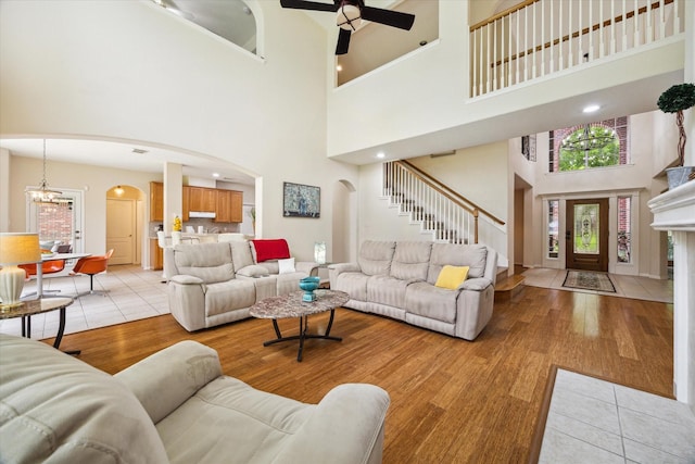 17326 Mesquite Brush Ln, Houston, TX 77095 - living room with arched walkways, a high ceiling, stairs, a ceiling fan, and light wood finished floors