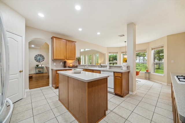 17326 Mesquite Brush Ln, Houston, TX 77095 - kitchen with white appliances, arched walkways, light tile patterned floors, a center island, and light countertops