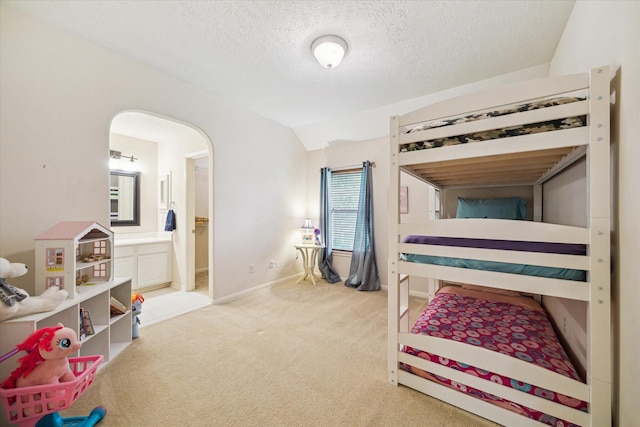 17326 Mesquite Brush Ln, Houston, TX 77095 - bedroom with light colored carpet, arched walkways, a textured ceiling, lofted ceiling, and connected bathroom